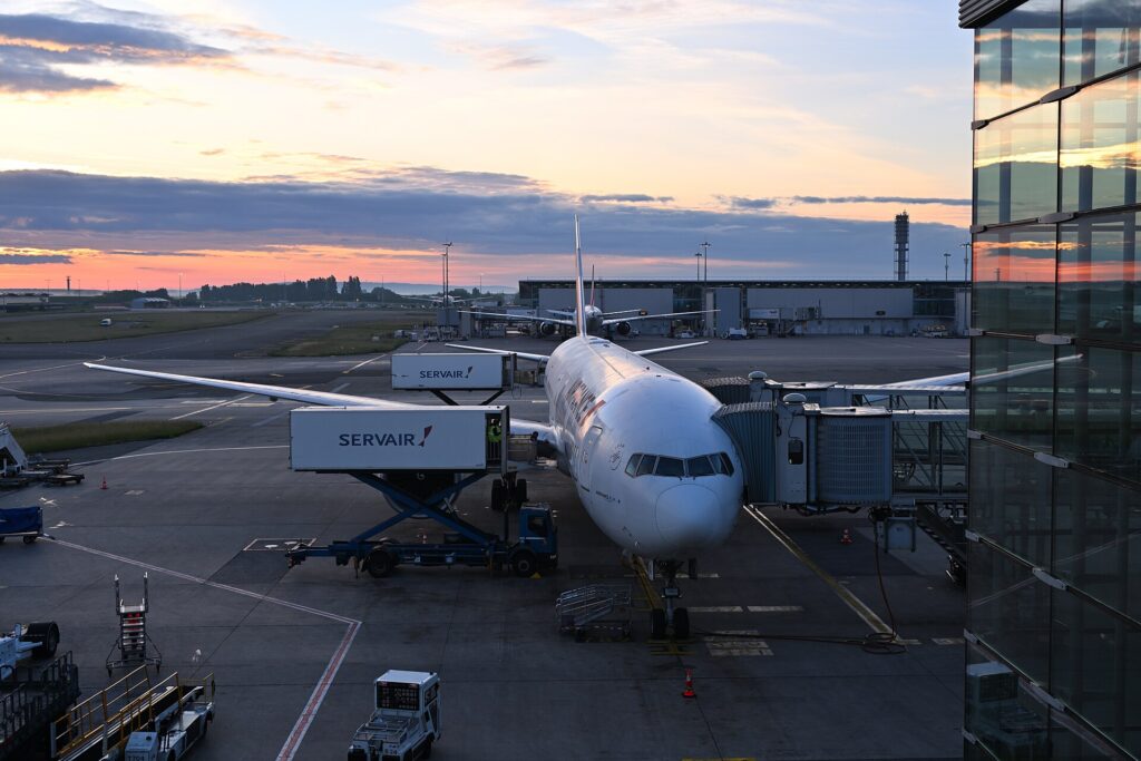 An Air France Boeing 777-300ER parked at a gate at Paris Charles de Gaulle airport at sunset
