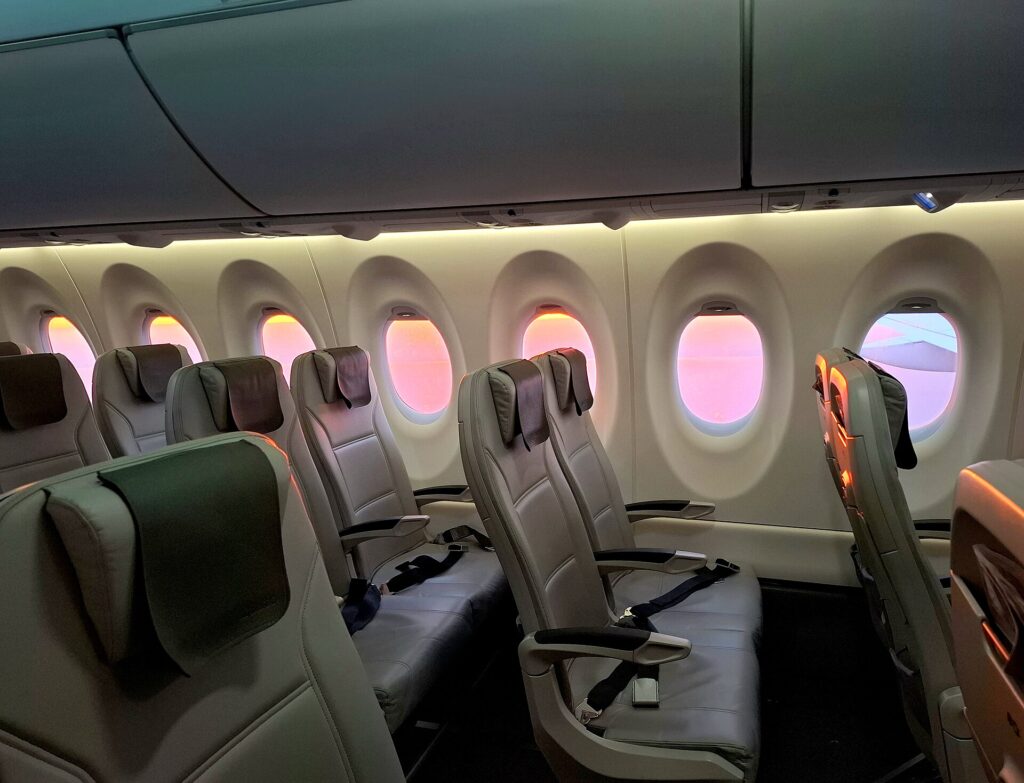 Economy cabin of an airBaltic Airbus A220 with grey leather seats and large windows