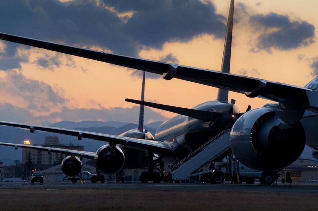 Several wide-body airliners parked side by side at Yokota Air Base at dusk after diverting from Narita