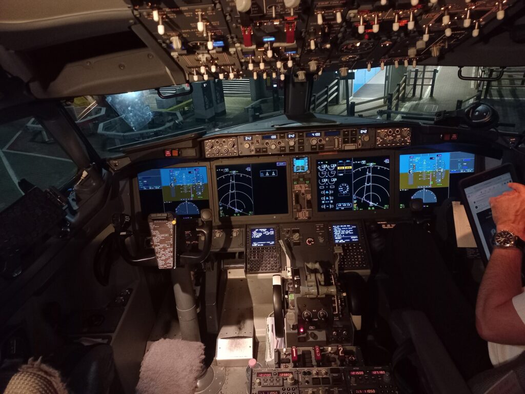 Boeing 737 MAX flight deck with a control yoke in front of each pilot seat and four large displays