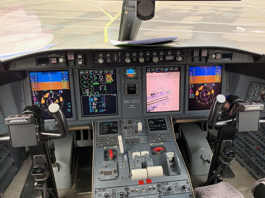Bombardier Challenger 605 flight deck with four large display screens and the centre console