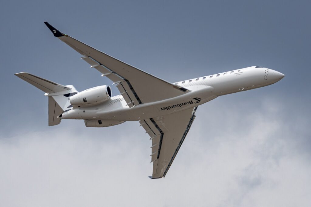 Bombardier Global 8000 N100BD banking in flight, seen from below with its swept wings and two rear engines