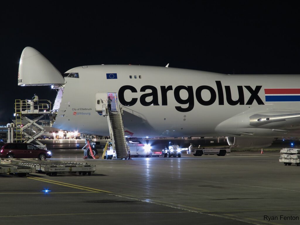 Cargolux Boeing 747-8F at night with its nose cargo door raised and a loader at the front