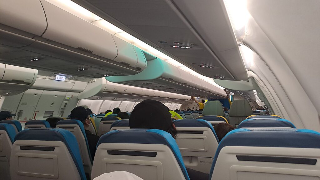 Economy cabin of a Cebu Pacific Airbus A330-900neo with passengers boarding under large overhead bins