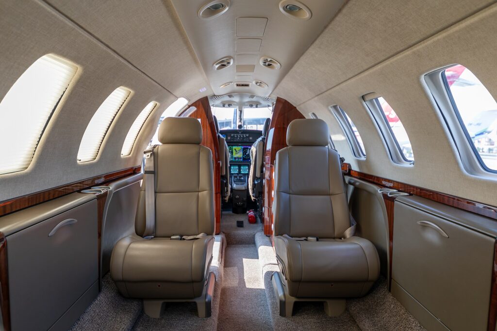 Cabin of a Cessna Citation CJ3+ with two cream leather seats and the cockpit beyond