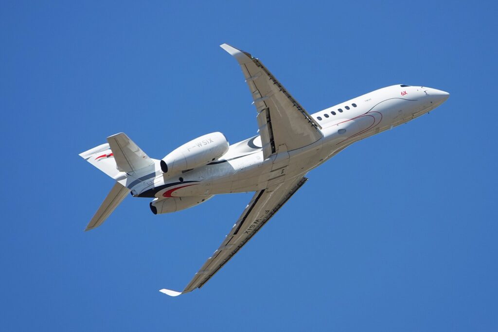 Dassault Falcon 6X seen from below in a steep bank against a blue sky