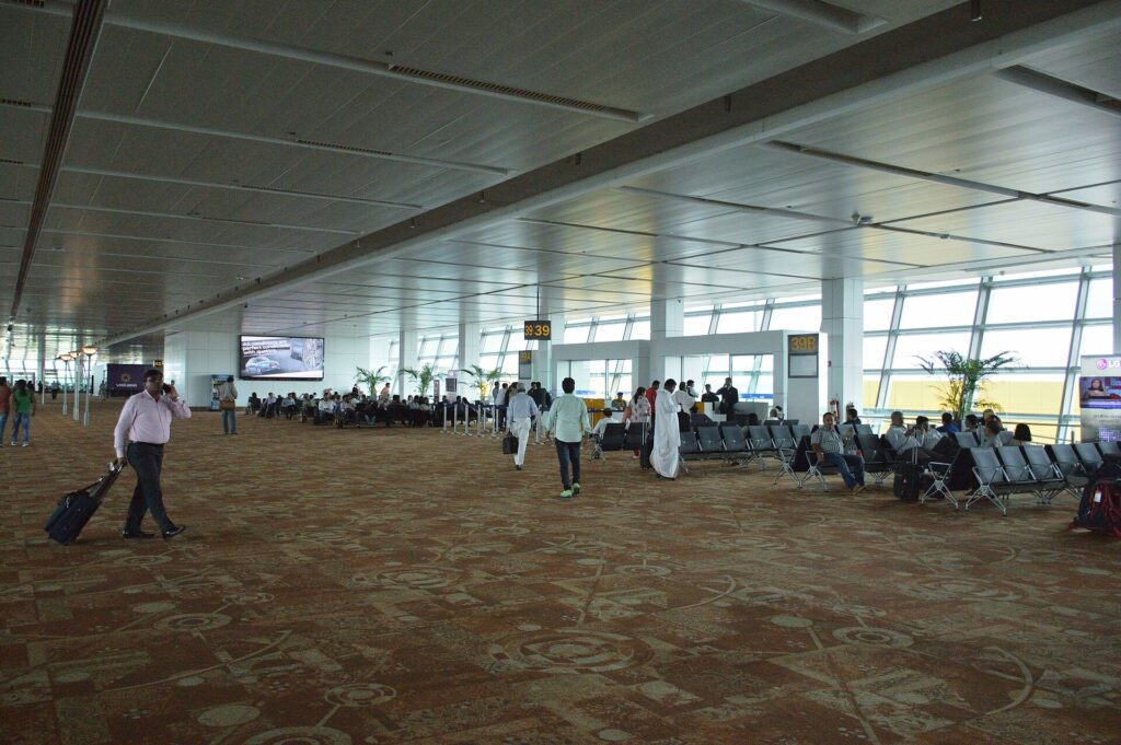 Passengers walking through the carpeted gate area inside Terminal 3 at Delhi airport