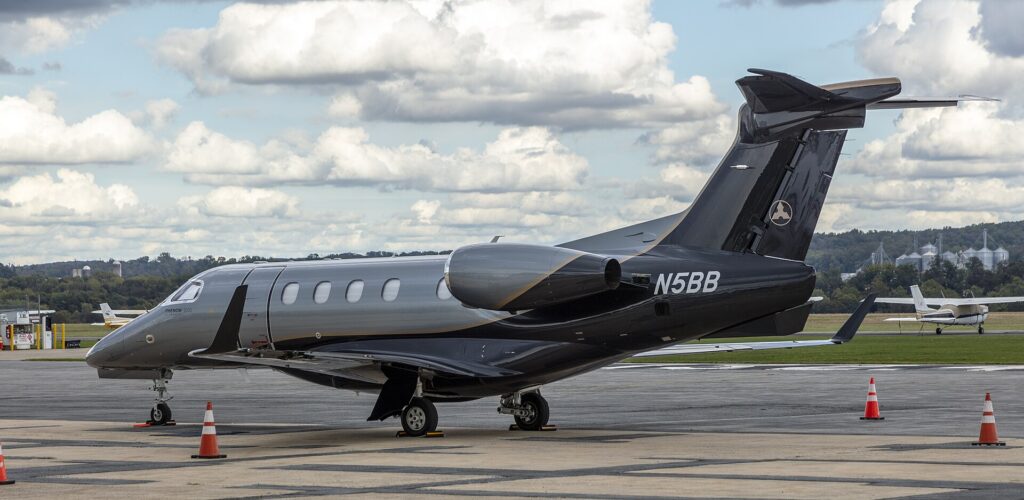 Dark grey Embraer Phenom 300E N5BB parked on the apron with its T-tail