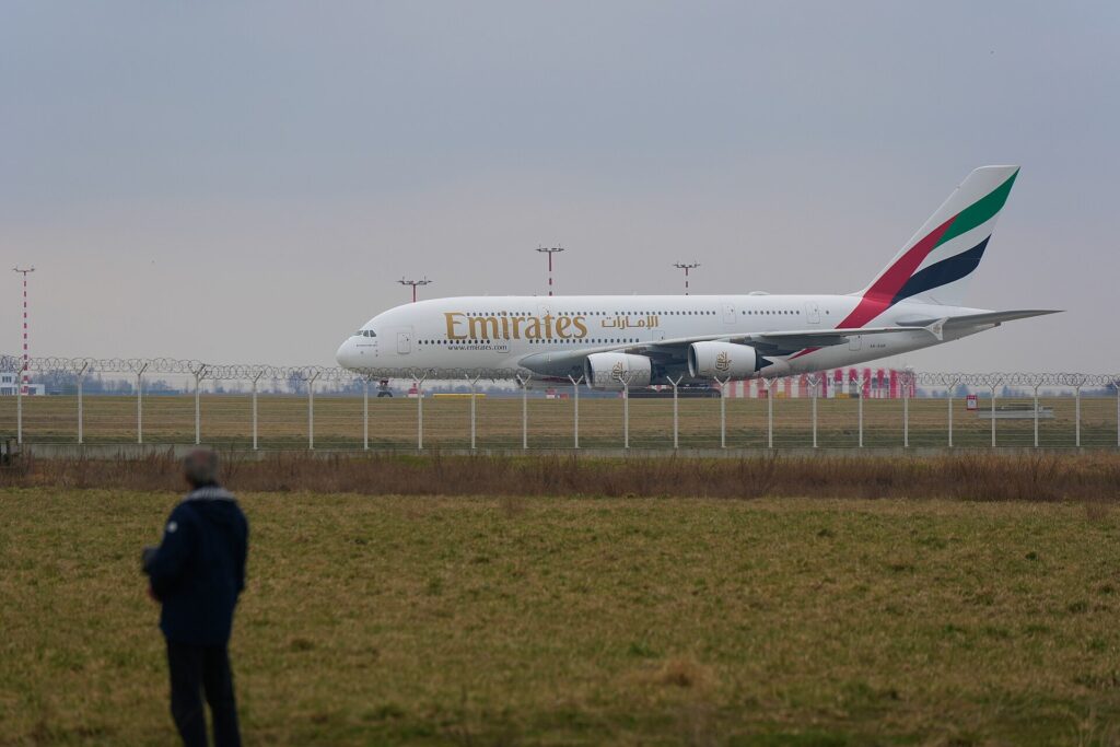 Emirates Airbus A380 A6-EUP taxiing at Prague airport behind a perimeter fence while a spotter watches