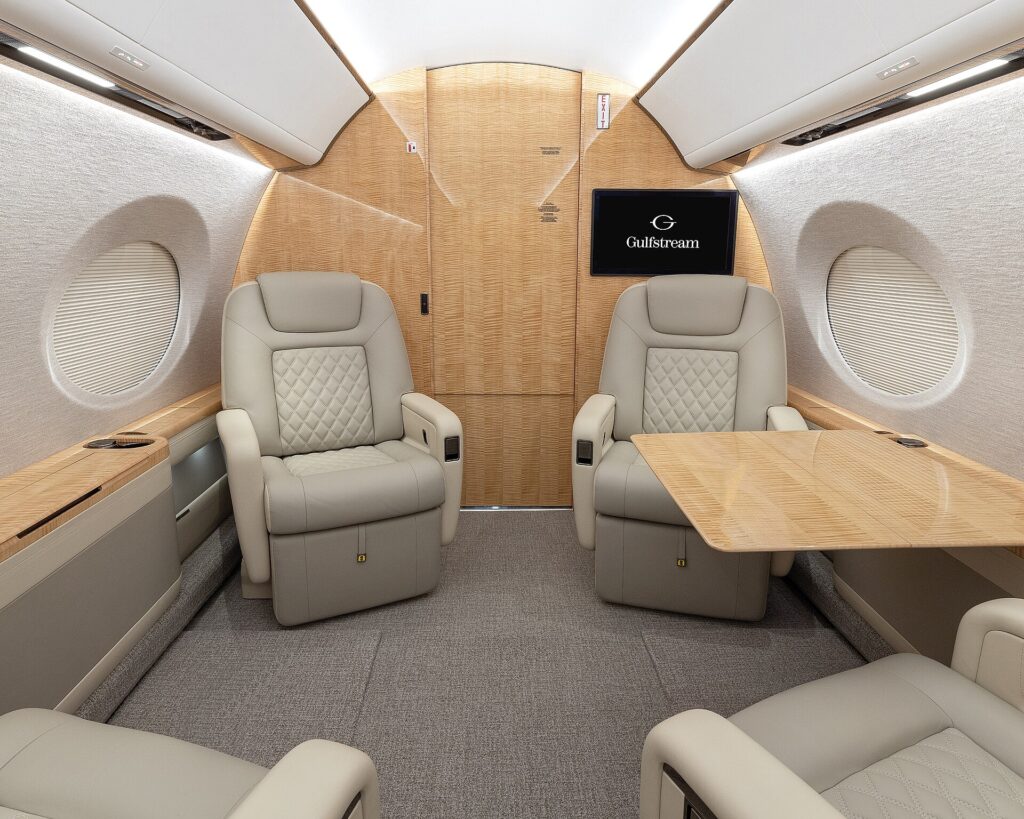 Two cream leather club seats facing each other in a Gulfstream G500 cabin with large oval windows