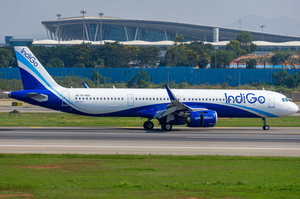 IndiGo Airbus A321neo taking off past a terminal building