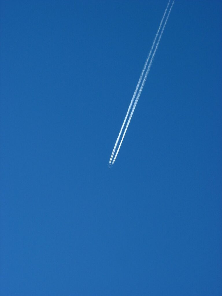 A jet airliner high in a deep blue sky leaving two white contrails
