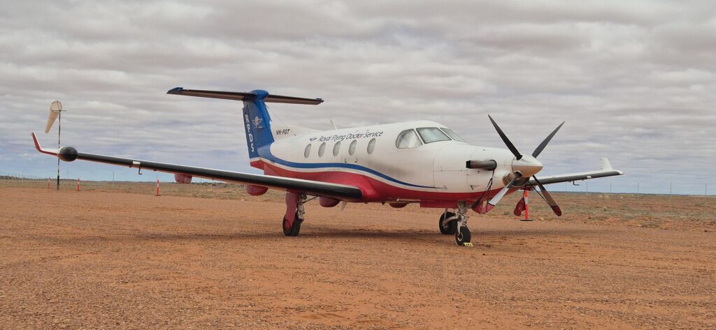 Royal Flying Doctor Service Pilatus PC-12 parked on a red dirt airstrip in South Australia