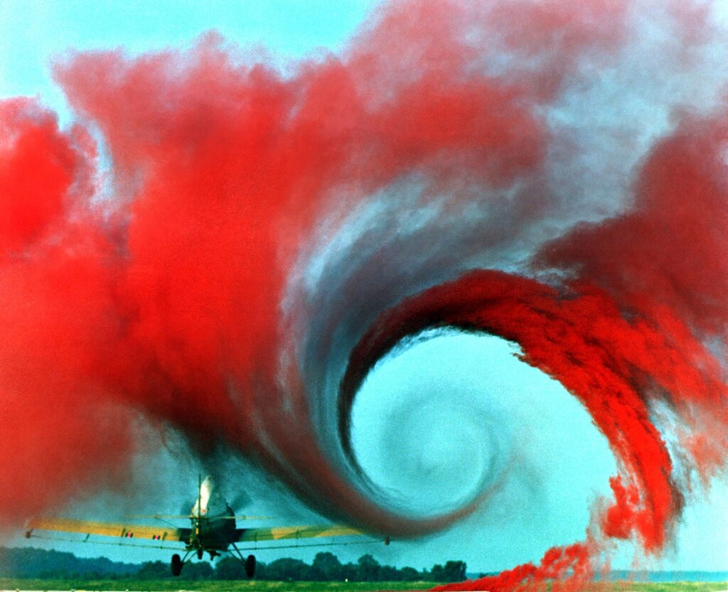 Red smoke showing a spiralling wingtip vortex behind a small aircraft in a NASA test